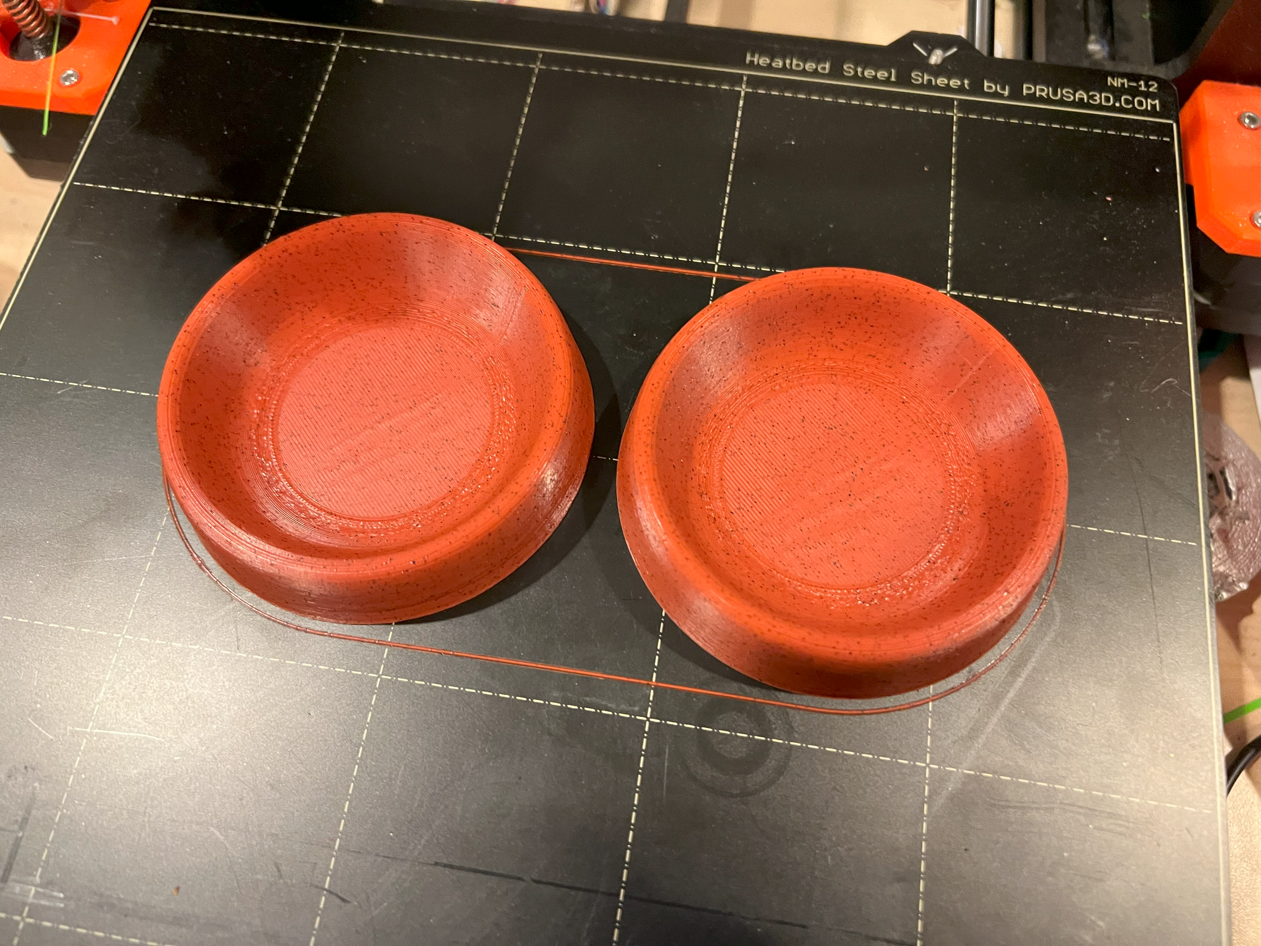 2 red 3d printed gaming trays on a printer bed